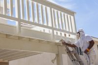 House Painter Spray Painting A Deck of A Home